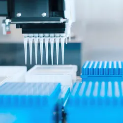 An automated liquid handling system picks microtips from tip boxes to aspirate a reaction component.