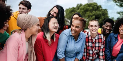 A multiethnic diverse group of people having fun outdoors and smiling at the camera.