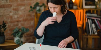 A woman spits into a saliva collection pouch as she prepares to examine her blood.