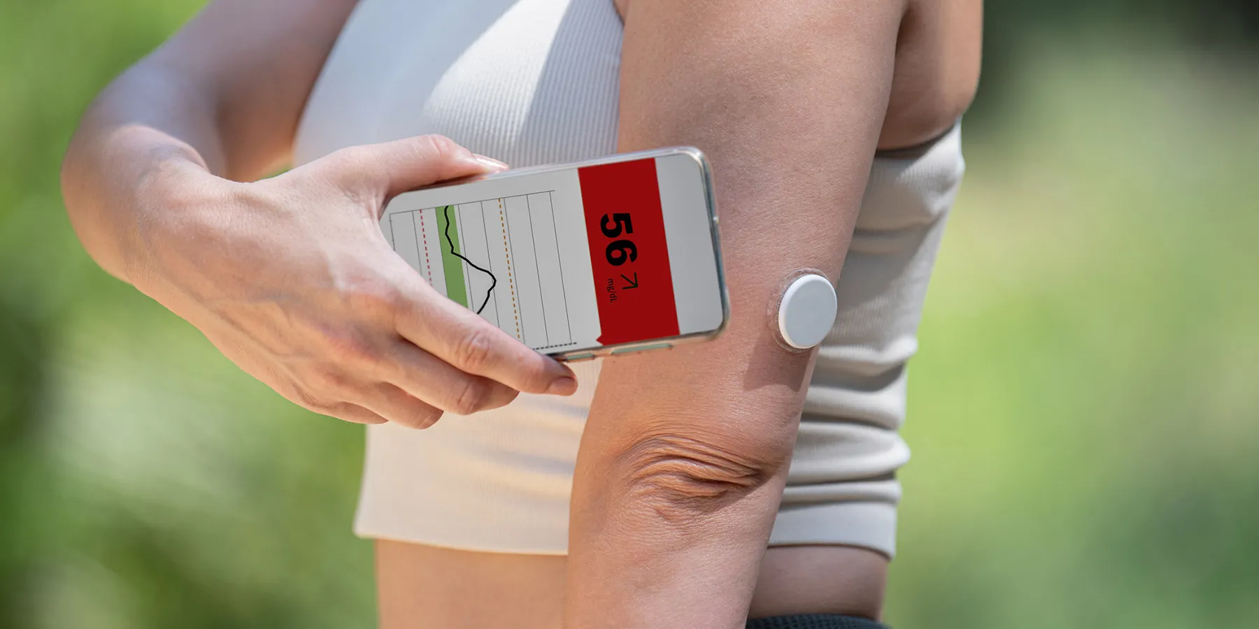 A person with a continuous glucose monitor checks blood glucose levels on a smartphone app.
