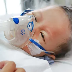 A caregiver puts on a nebulization mask on an infant with a respiratory infection in a hospital setting.