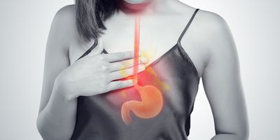 A woman places her right hand on her chest and a vector of the human stomach is placed on her image.