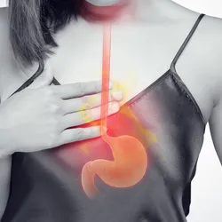 A woman places her right hand on her chest and a vector of the human stomach is placed on her image.