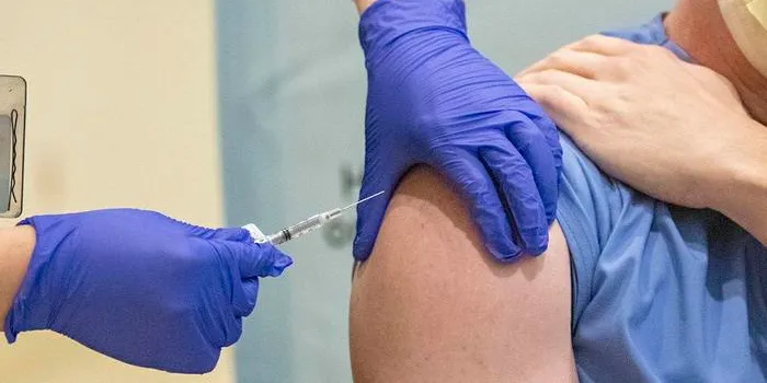 Photo of a person receiving an RNA-based vaccine injected in their upper arm.