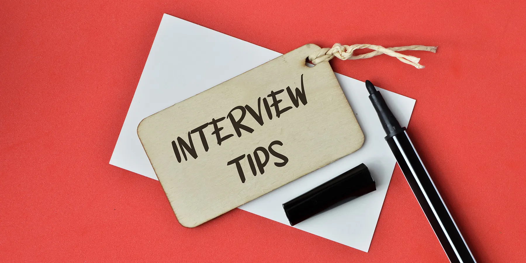 Photo of a wooden tag that reads “interview tips” on a red background.