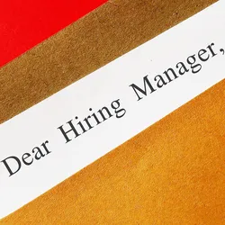 Photo of a letter-sized envelope with the text “Dear Hiring Manager” written on the top of a piece of paper sticking out of the envelope.