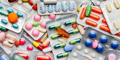 Photo of a large pile of different colorful antibiotics pills inside blister packaging.