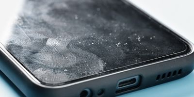Close up photo of a smartphone with a white powdery substance and fingerprints on its surface.