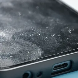 Close up photo of a smartphone with a white powdery substance and fingerprints on its surface.