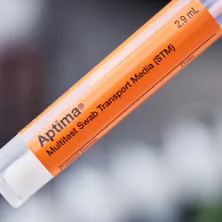 Orange vial with "Aptima Multitest Swab Transport Media (STM)" written in black lettering with grey background.