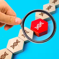 Photo of a person holding a magnifying glass over a wood chip with the image of a DNA helix on it with a blue background.