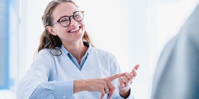 Photo of a White female medical laboratory manager smiling while conducting a hiring interview with a potential lab candidate.
