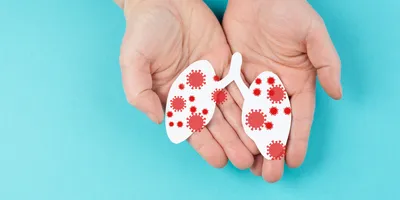 Illustration of a pair of human hands holding a paper cutout of lungs with infections.