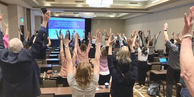 Participants at conference raise arms upward