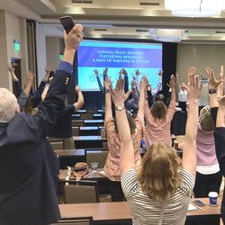 Participants at conference raise arms upward