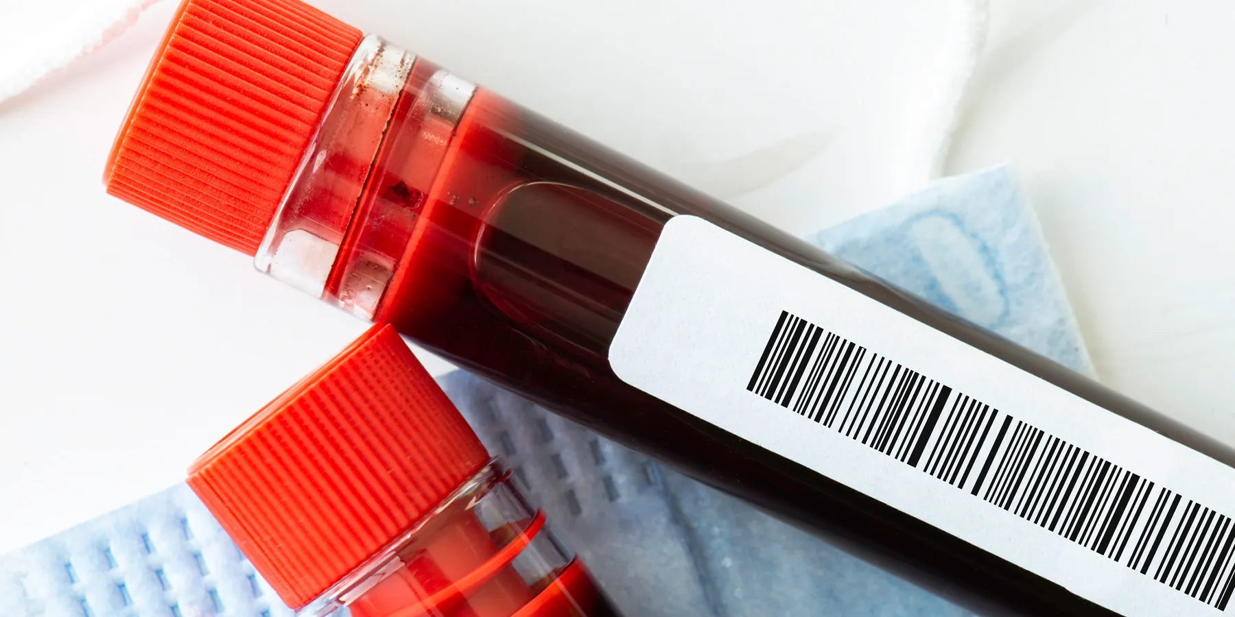Up-close photo of blood test tubes with barcode labels on a clinical laboratory bench.