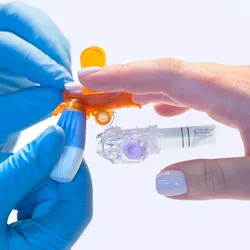 Photo of a technician holding a patient's hand and taking a sample of blood in the BD MiniDraw