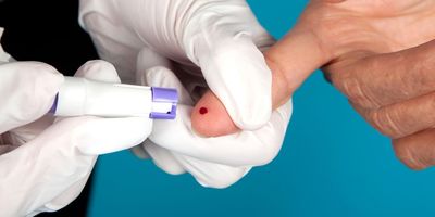 Photo of a healthcare worker pricking the finger of a patient to take a small blood sample.