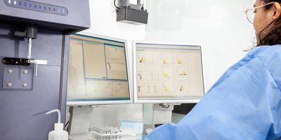 Photo of a clinical laboratory scientist wearing PPE and performing a flow cytometry analysis on T cells in diabetes samples.