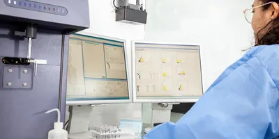 Photo of a clinical laboratory scientist wearing PPE and performing a flow cytometry analysis on T cells in diabetes samples.