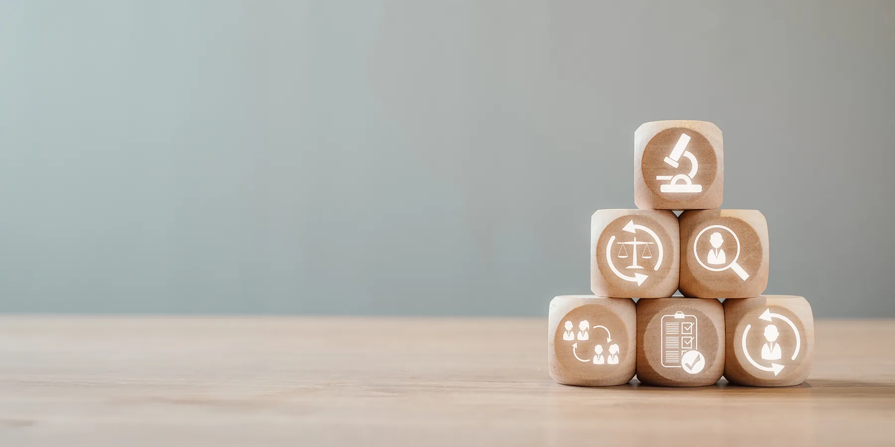 Photo of wooden blocks stacked in a pyramid with symbols related to the clinical laboratory carved into the fronts.