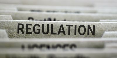 Photo of the word “regulation” in bold capital letters on the side of a file folder.