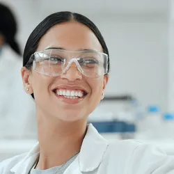 Photo of a smiling clinical laboratory professional wearing PPE in the lab giving a high five to another laboratorian.