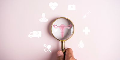 Illustration of a person’s hand holding a magnifying glass on top of a drawing of the uterus and fallopian tubes on a pink background.