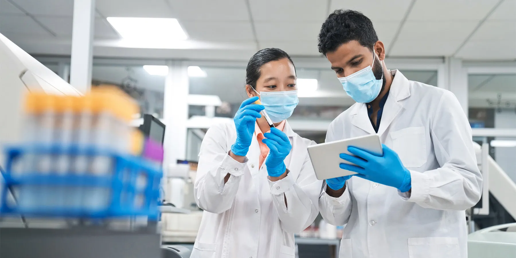 Two clinical laboratory scientists wearing PPE in the laboratory hold a clipboard and review the milestones toward the new FDA LDT Final Rule.