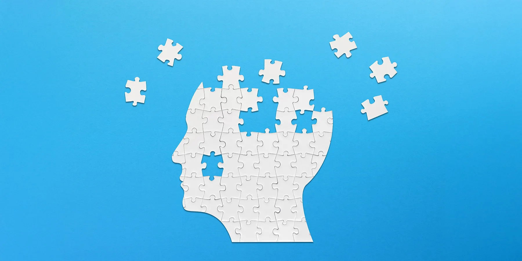  Illustration of a brain-shaped white jigsaw puzzle on blue background.