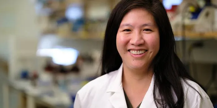 Portrait of Judith Su wearing a white lab coat at the University of Arizona’s Little Sensor Lab.
