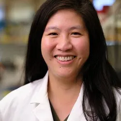 Portrait of Judith Su wearing a white lab coat at the University of Arizona’s Little Sensor Lab.