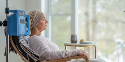 Photo of a woman sitting in a hospital chair with an IV and undergoing treatment for ovarian cancer.