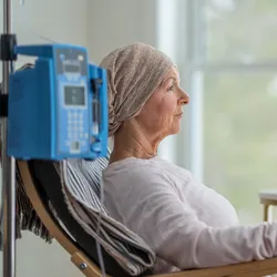 Photo of a woman sitting in a hospital chair with an IV and undergoing treatment for ovarian cancer.