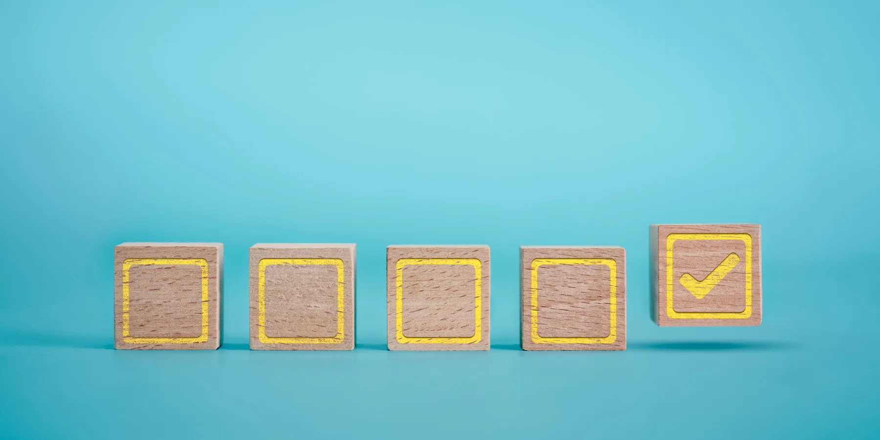 Photo of wood blocks with a checklist drawn on them against a blue background.