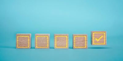 Photo of wood blocks with a checklist drawn on them against a blue background.