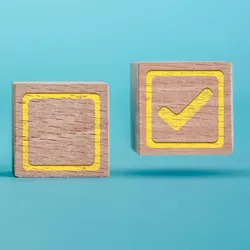 Photo of wood blocks with a checklist drawn on them against a blue background.