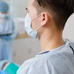 Photo of a clinician wearing PPE and conducting a colonoscopy for colon cancer screening in an emergency department patient.