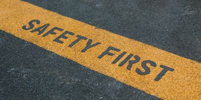Photo of a roadway with a painted yellow line with the words ‘safety first’ written in the paint.