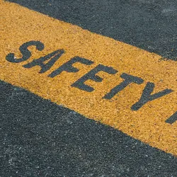 Photo of a roadway with a painted yellow line with the words ‘safety first’ written in the paint.