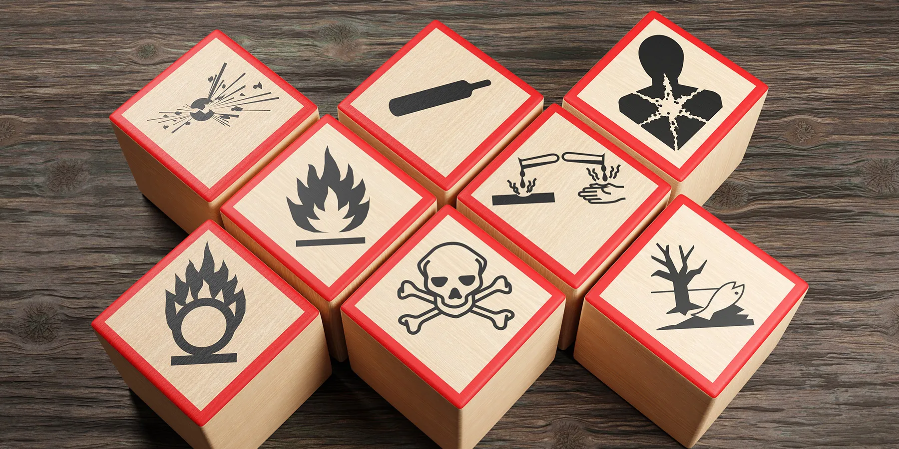Photo of wooden blocks showing different symbols of chemical hazard warnings on wood table.