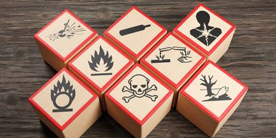 Photo of wooden blocks showing different symbols of chemical hazard warnings on wood table.