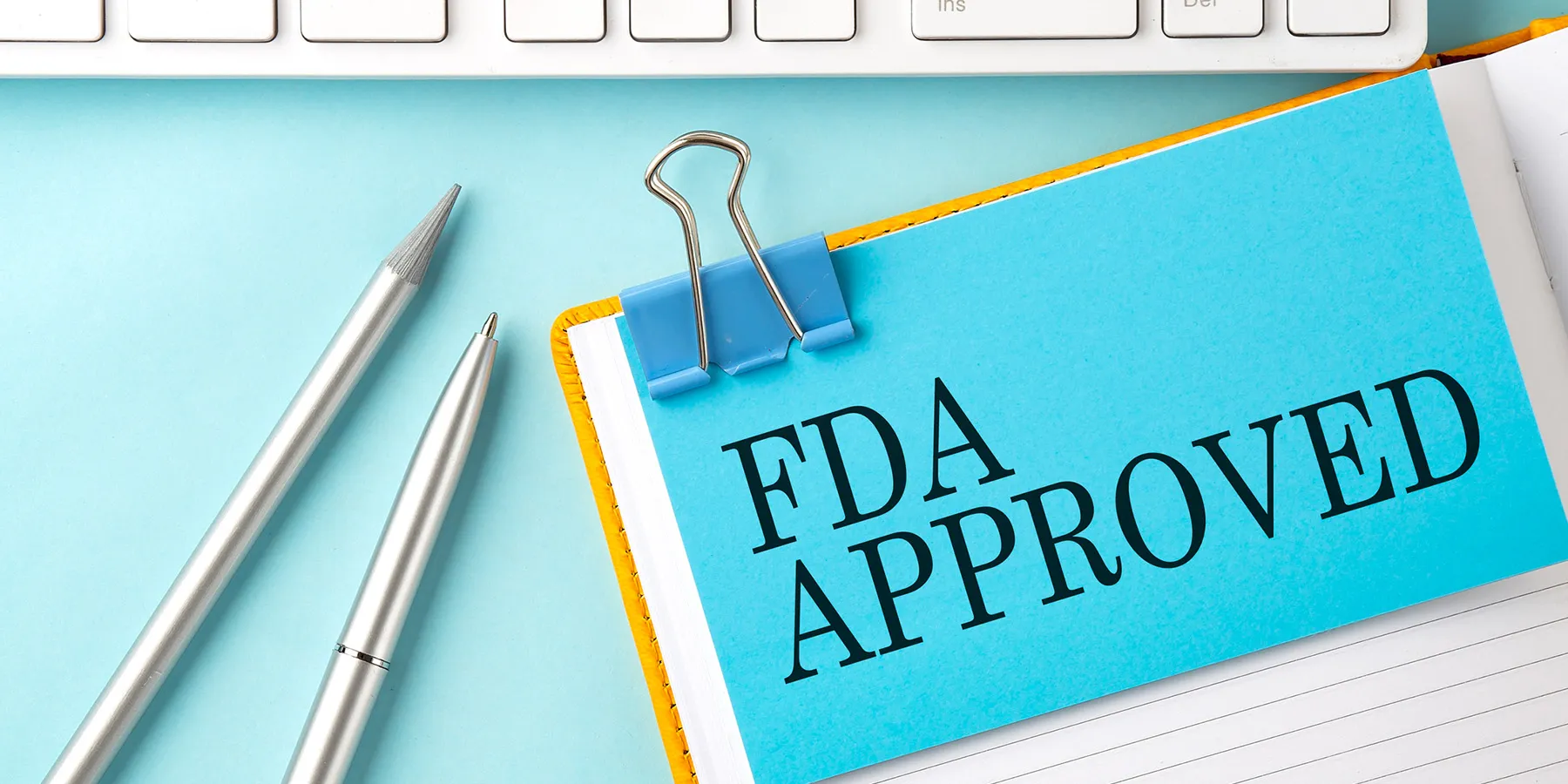 Photo of a piece of paper that reads "FDA Approved" on a clickboard.