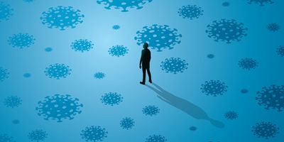 Illustration of a person standing alone in the middle of a large room with COVID-19 virus particles scattered around the blue background.