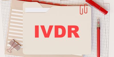 Photo of a document folder with the word “IVDR” on it in bold red letters and other office supplies on a desk.