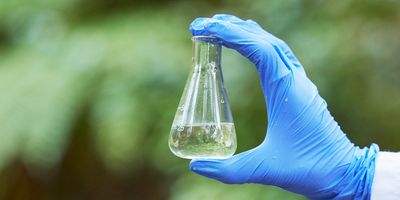Scientist holding a flask of water with a green background