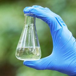 Scientist holding a flask of water with a green background