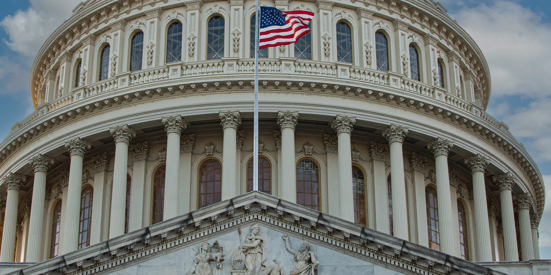 Photo of the front of the US Capitol Building, the seat of the United States Congress, with a USA flag flying in front and blue sky and clouds in the background. ADLM hosted a congressional briefing on laboratory-developed tests there on February 20, 2025.