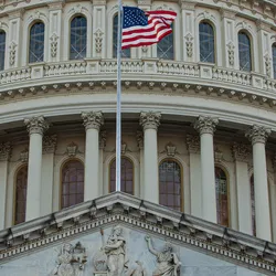 Photo of the front of the US Capitol Building, the seat of the United States Congress, with a USA flag flying in front and blue sky and clouds in the background. ADLM hosted a congressional briefing on laboratory-developed tests there on February 20, 2025.