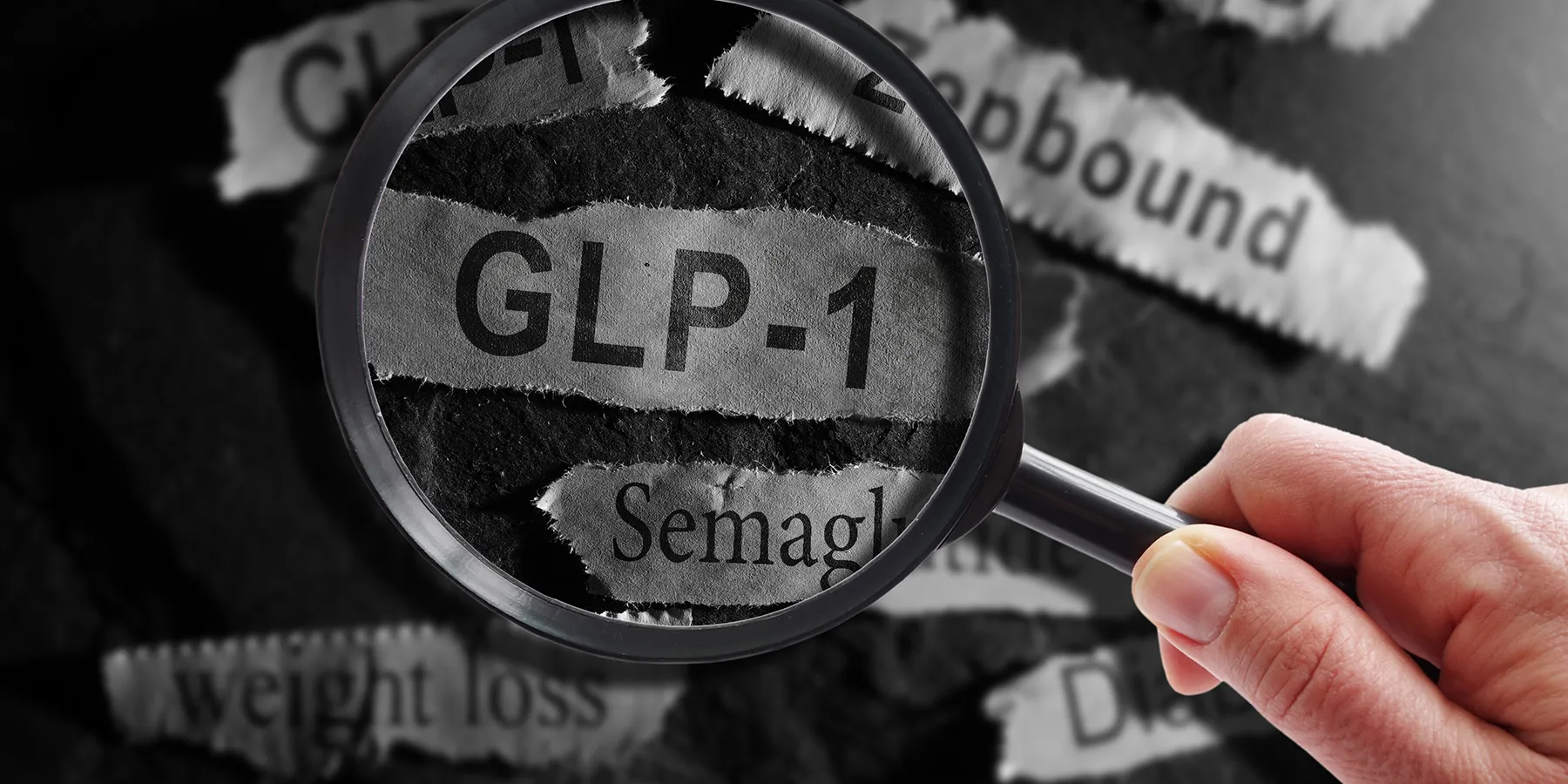 Photo of someone holding a magnifying glass over the word “GLP-1” against a black background.
